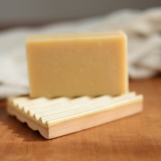 Bar of soap on a ceramic soap dish with a neutral background