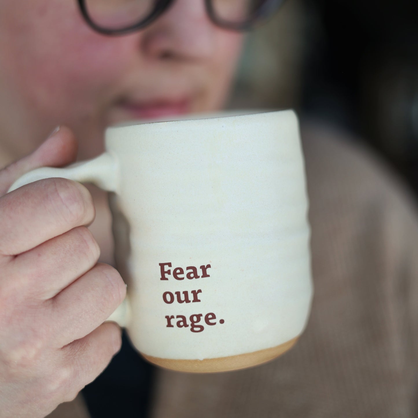 Person holding a mug with 'Fear our rage.' text