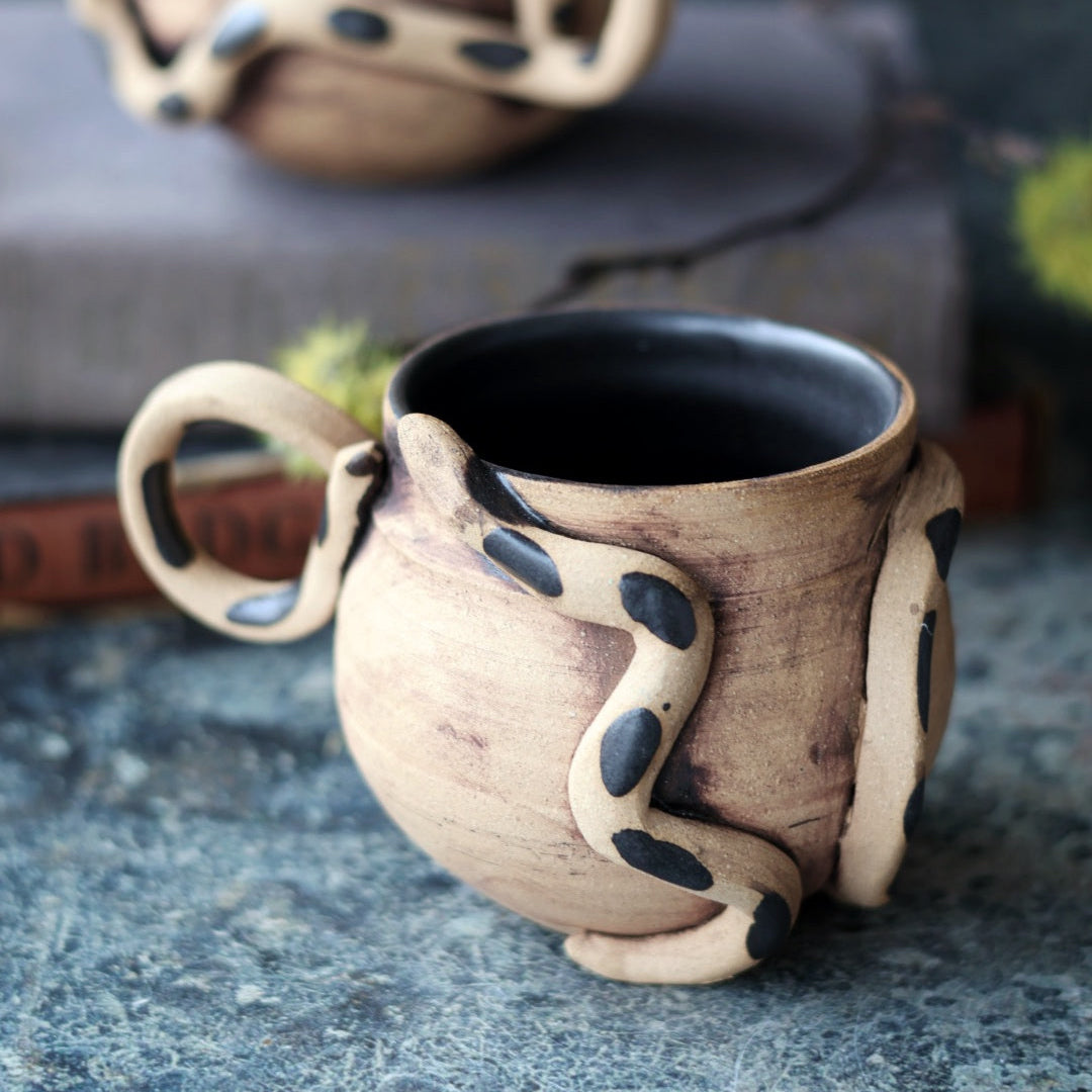 Handmade ceramic mug with unique design on a textured surface