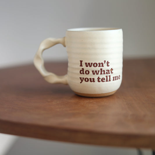 Cream mug with “I won’t do what you tell me” text on a wooden table