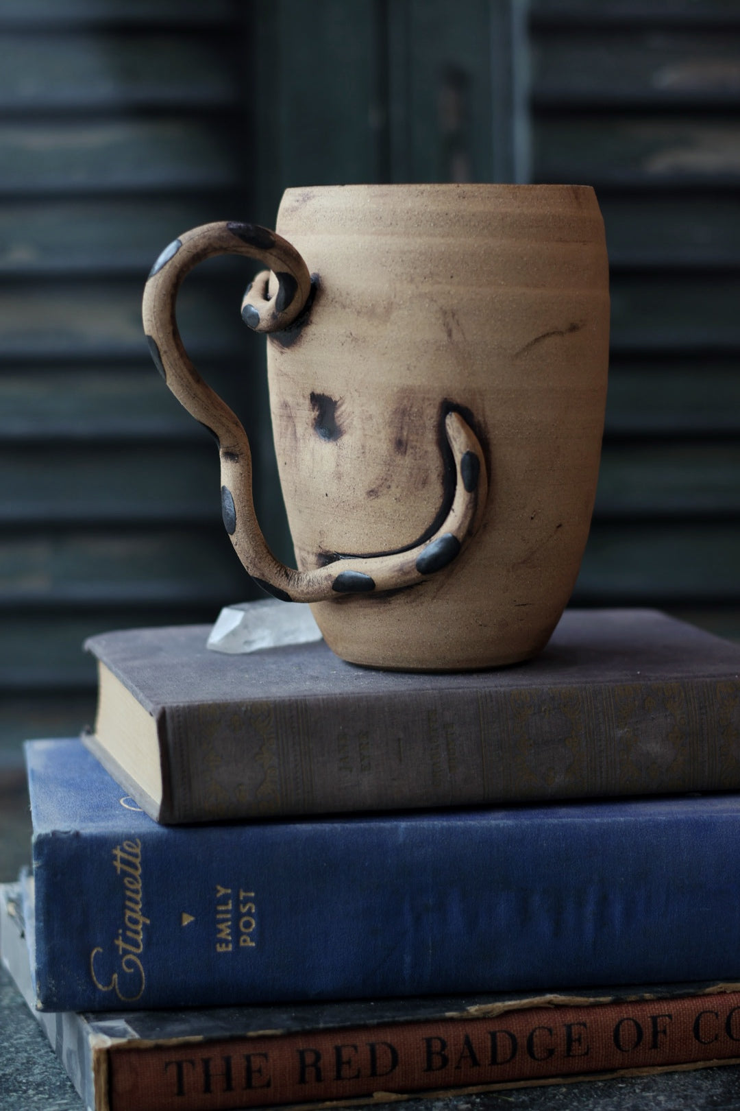 Ceramic mug with a unique handle on top of books