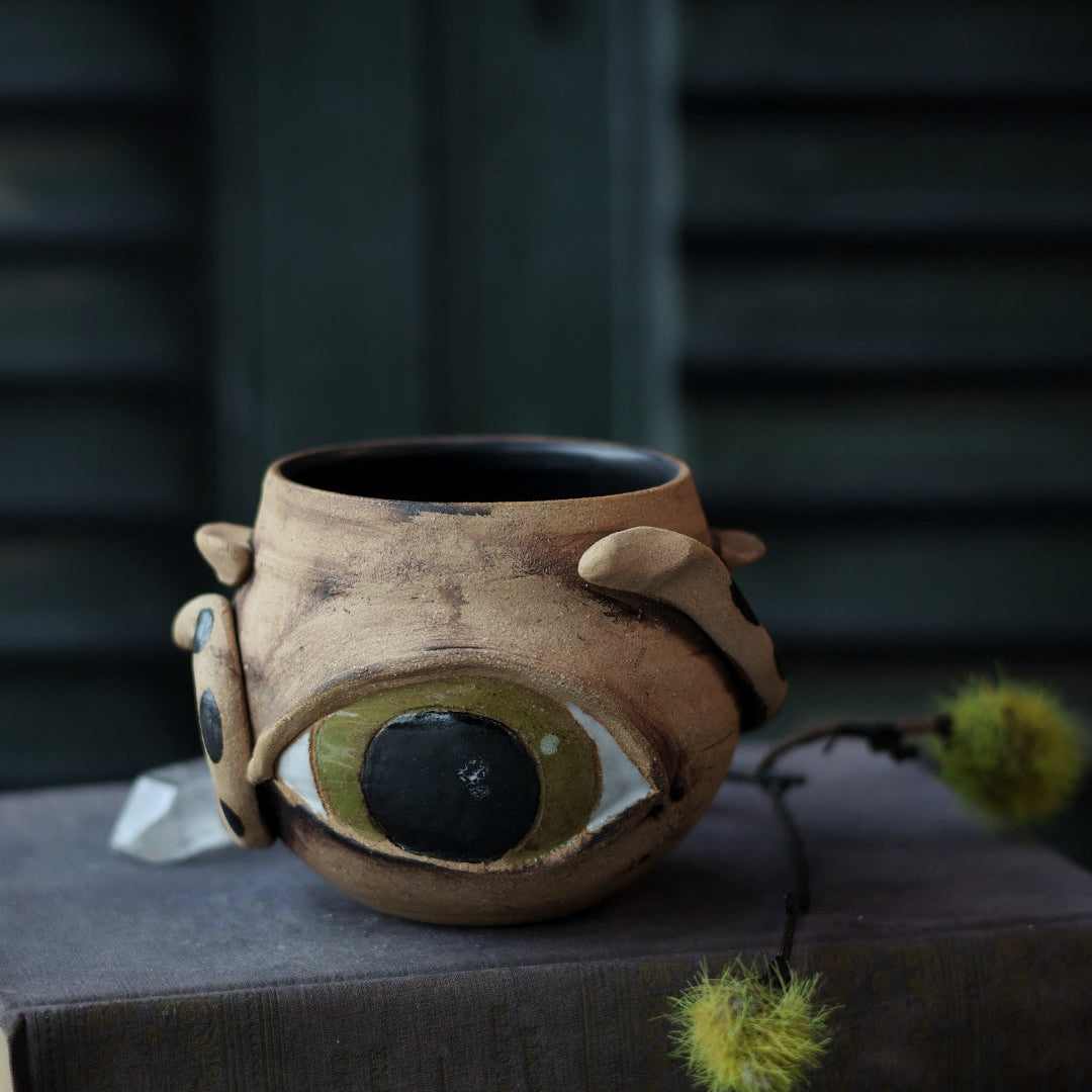 Ceramic mug with eye design on a dark surface