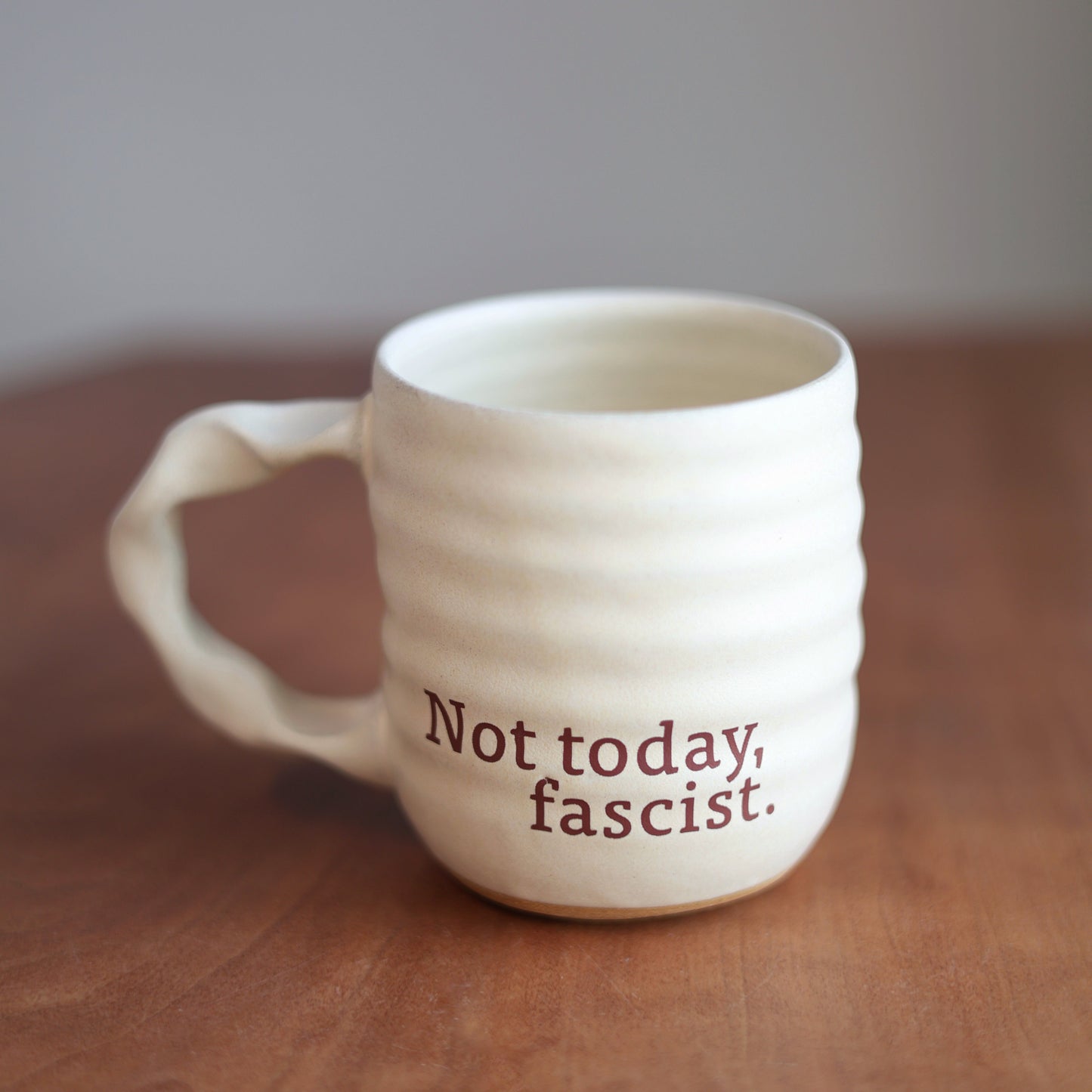 Off White handmade ceramic companion mug with 'Not today, fascist.' text on a wooden surface.