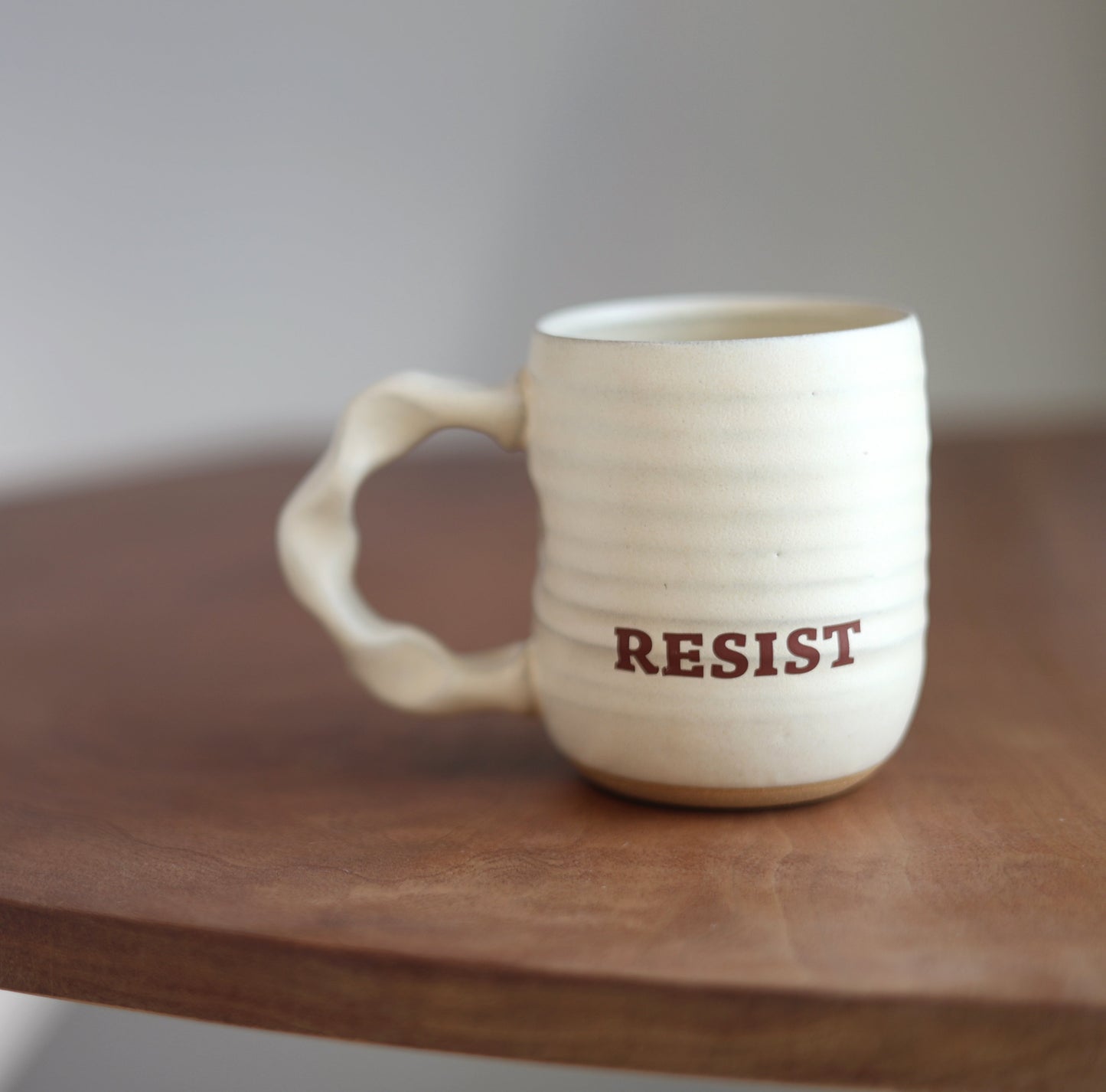 Off White mug with 'RESIST' printed on it on a wooden table