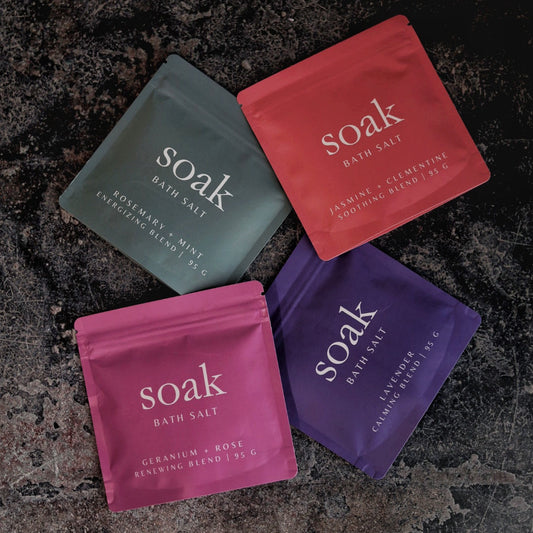 Four packets of 'soak' bath salts on a textured dark surface