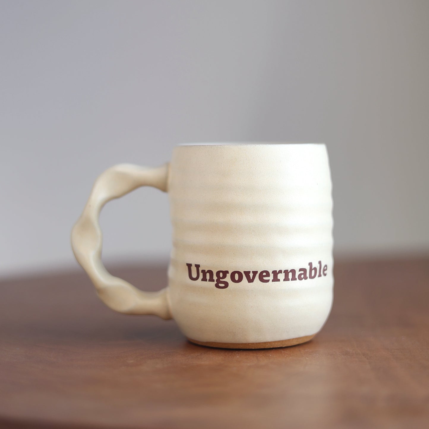 White mug with 'Ungovernable' text on a wooden surface