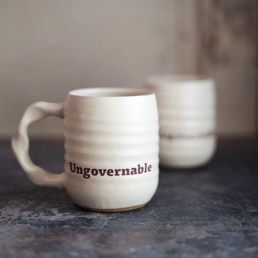 White ceramic mug with 'Ungovernable' text on a dark surface