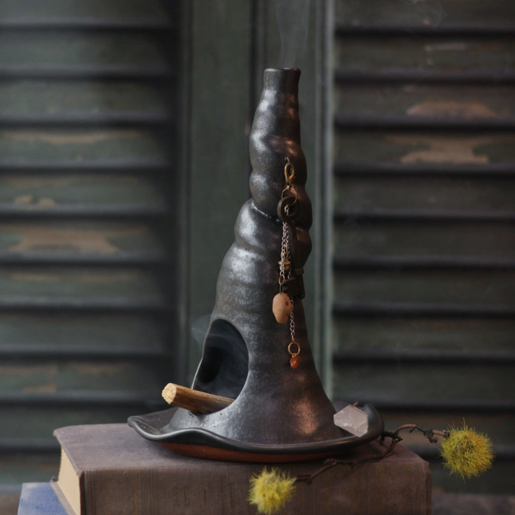 Decorative object resembling a witch's hat on top of books with a dark background