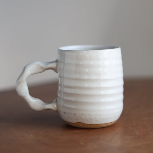 White ceramic cup with handle on a plain background