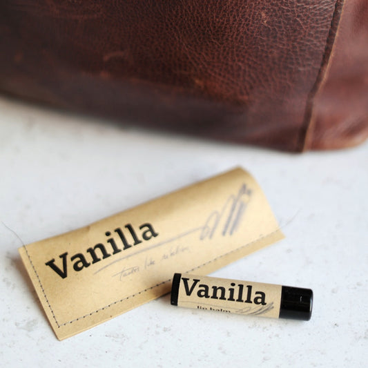Vanilla scented lip balm with a leather bag in the background