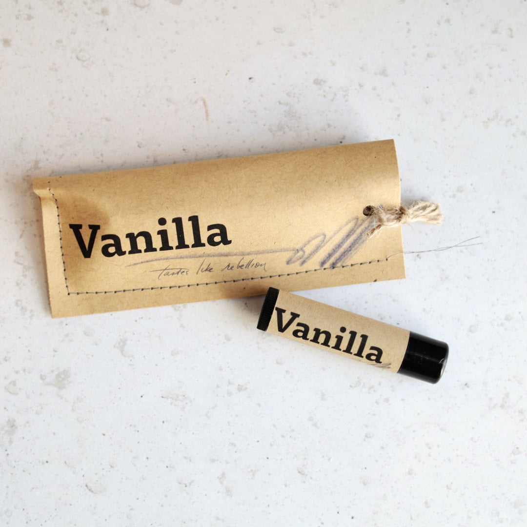 Vanilla-scented lip balm and packaging on a light textured surface