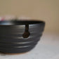 Black ceramic yarn bowl on a light surface with a blurred background