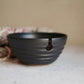 Black ceramic yarn bowl on a light surface with a neutral background