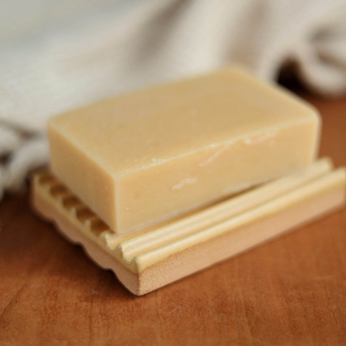Bar of soap on a ceramic soap dish with a blurred background