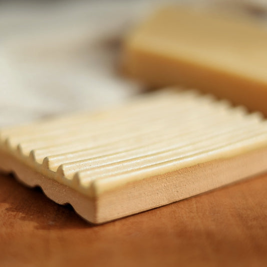 Close-up of a rectangular soap bar with textured surface on a wooden surface.