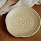 Beige ceramic dish with spiral design on a wooden surface
