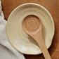 Wooden spoon on a beige ceramic plate with a wooden background