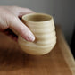 Hand holding a ceramic cup on a wooden surface with a blurred background