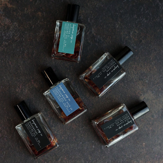 Five small perfume bottles with visible labels on a dark textured surface