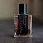 Small glass perfume oil bottle with a black label on a textured surface