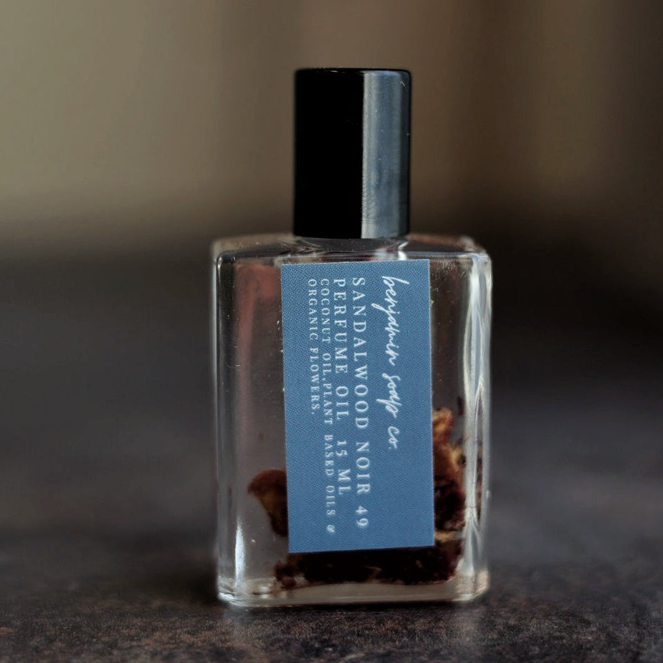 Small bottle of sandalwood perfume with a blue label on a dark surface