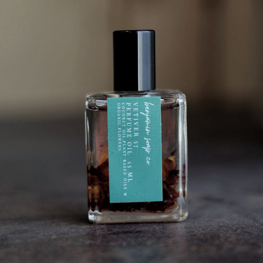 Small bottle of vetiver perfume oil with a teal label on a textured surface
