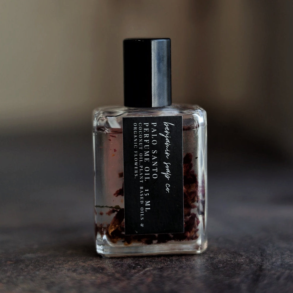 Small Palo Santo perfume bottle with a black cap on a dark surface