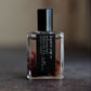 Small glass Woodberry perfume bottle with black cap and label on a textured surface