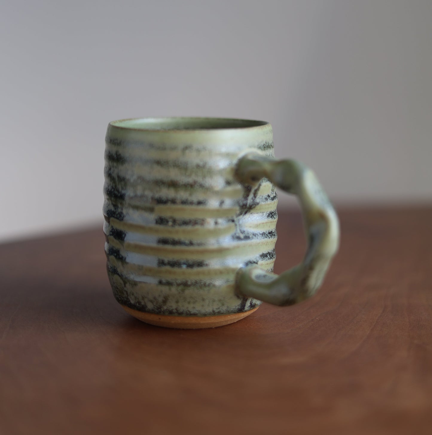 Moss green Ceramic companion mug with handle held by a hand against a neutral background