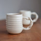 Two ceramic mugs on a wooden surface with a blurred background