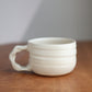 White ceramic cup with handle on a wooden surface