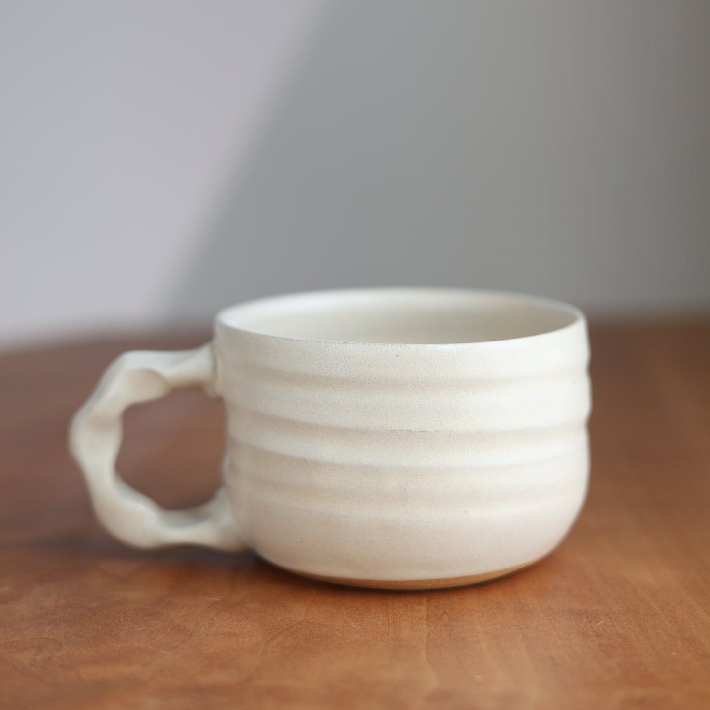 White ceramic cup with handle on a wooden surface