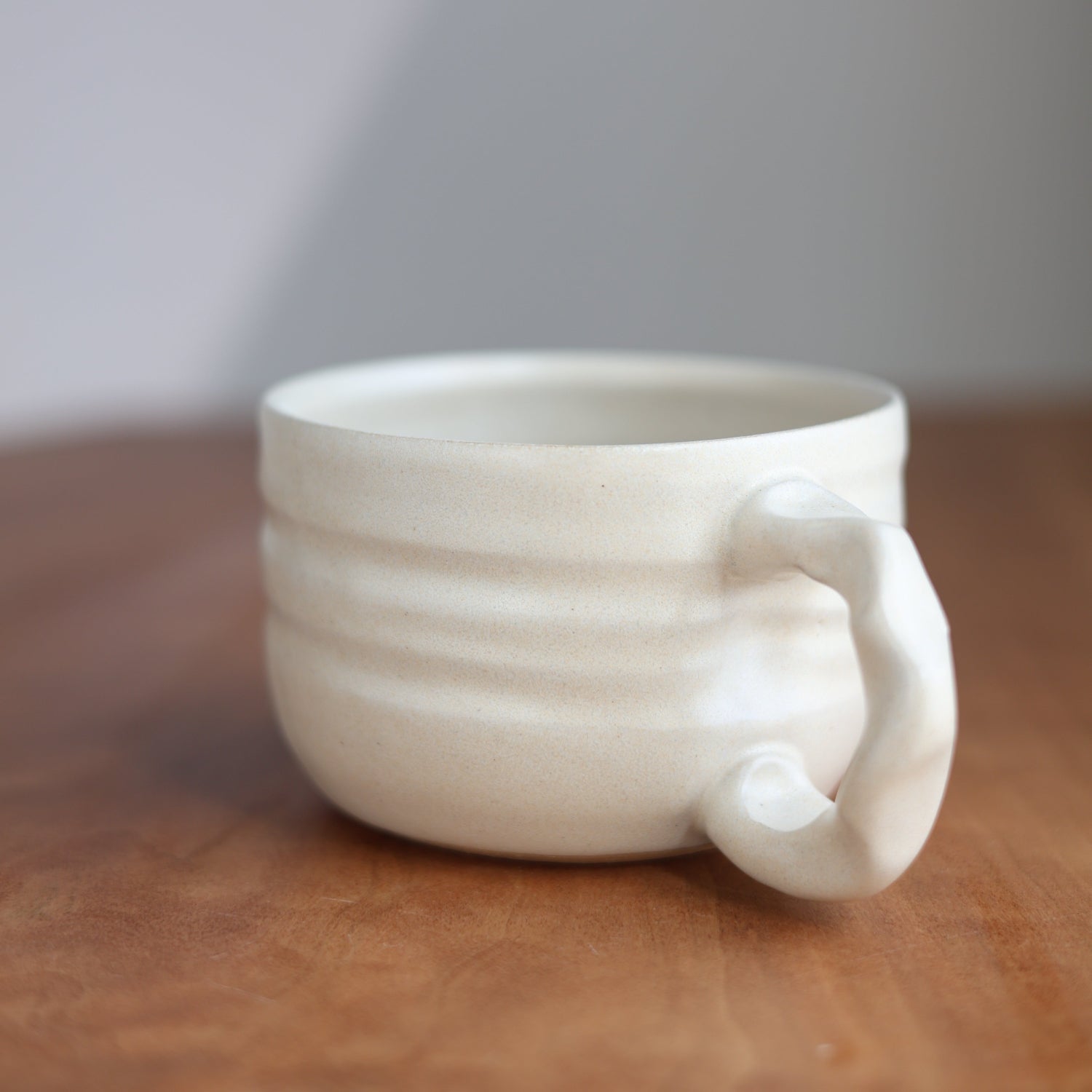 White ceramic cup with handle on a wooden surface