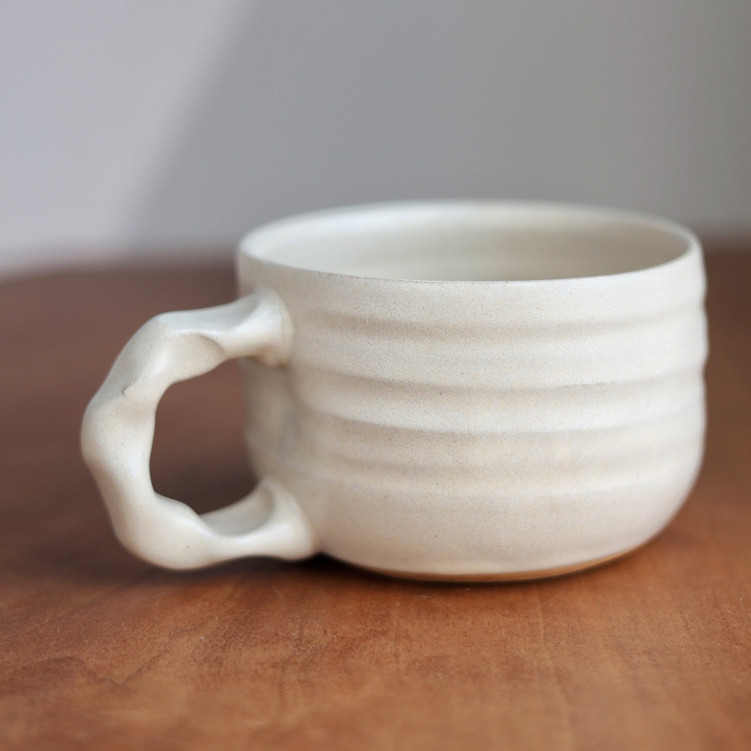 White ceramic mug on a wooden surface with a neutral background