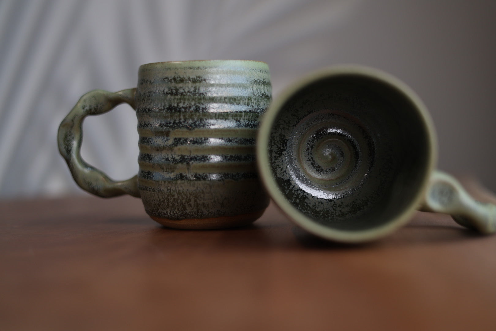 Two ceramic mugs with textured surfaces on a wooden surface.