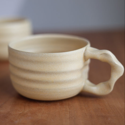 Beige ceramic mug with a handle on a wooden surface
