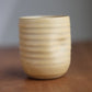 Beige ceramic cup with striped pattern on a wooden surface
