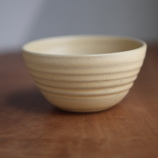 Beige ceramic bowl on a wooden surface with a blurred background