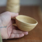 Hand holding a small ceramic bowl on a wooden surface