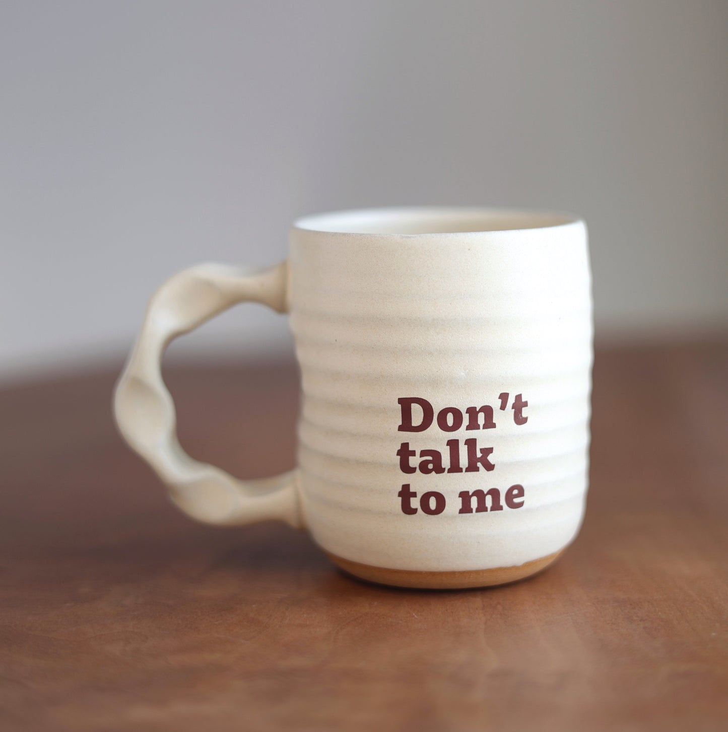 Off White mug with 'Don't talk to me' text on a wooden surface
