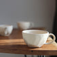 White ceramic faceted tea cups on a wooden table with a blurred background