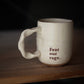 White mug with 'Fear our rage' text on a wooden surface