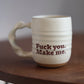 Cream “fuck you make me” ceramic mug with text on a wooden surface