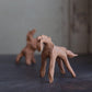 Two small clay figurines of horses on a textured surface with a blurred background.