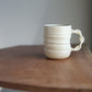 Cream handmade ceramic jumbo companion mug on a wooden table with a plain background