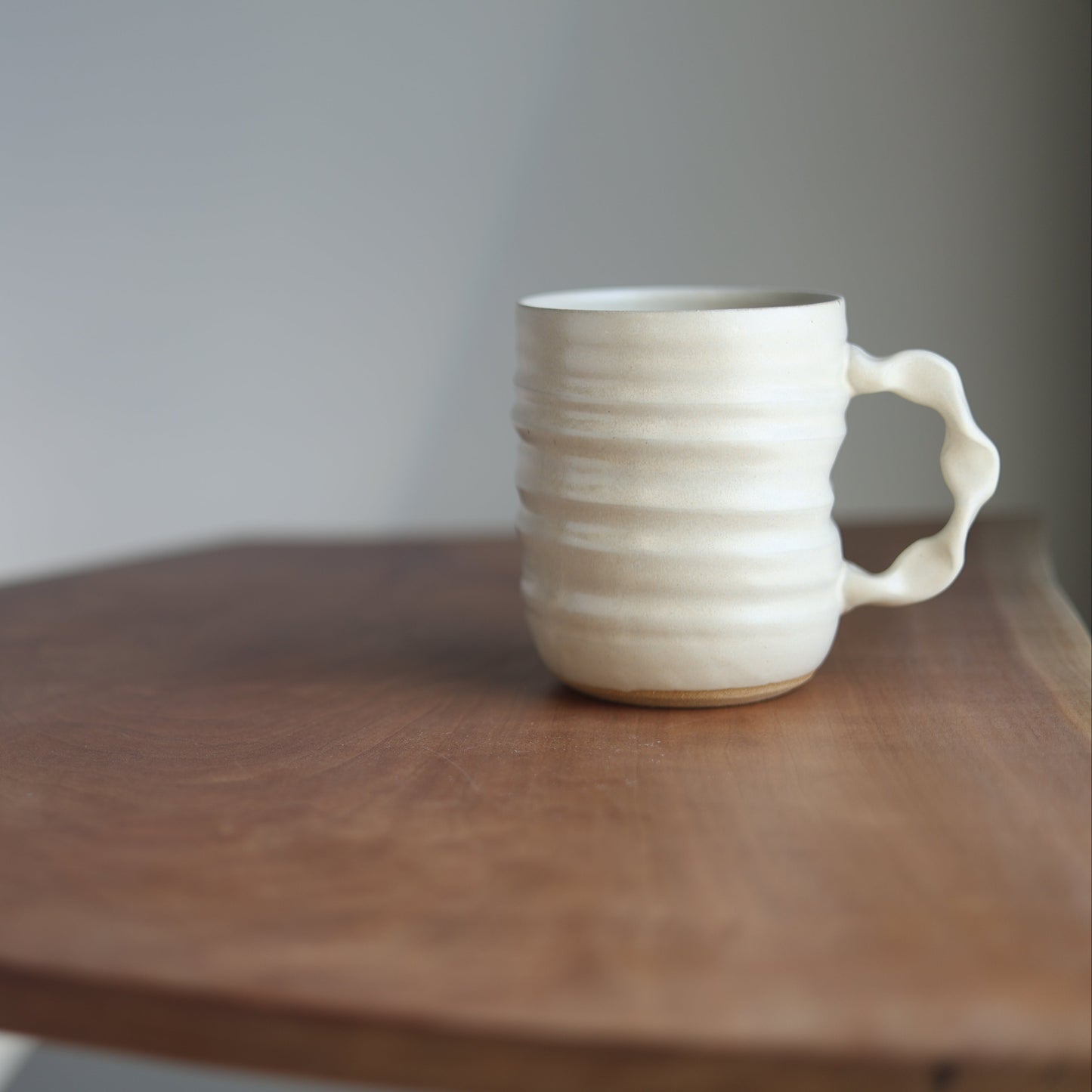 Cream handmade ceramic jumbo companion mug on a wooden table with a plain background