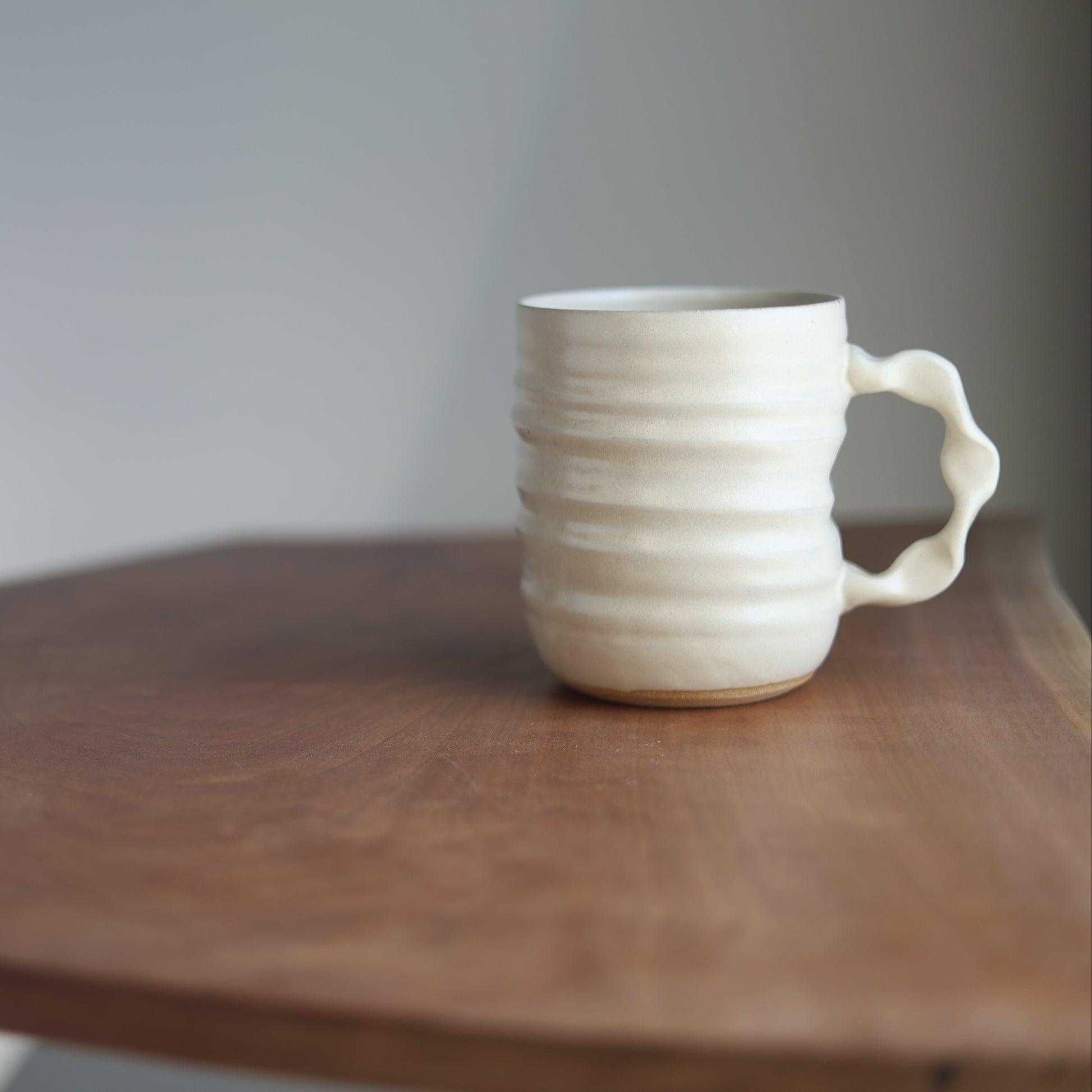 Cream handmade ceramic jumbo companion mug on a wooden table with a plain background