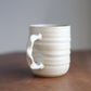 Cream handmade ceramic jumbo companion mug on a wooden surface with a gray background