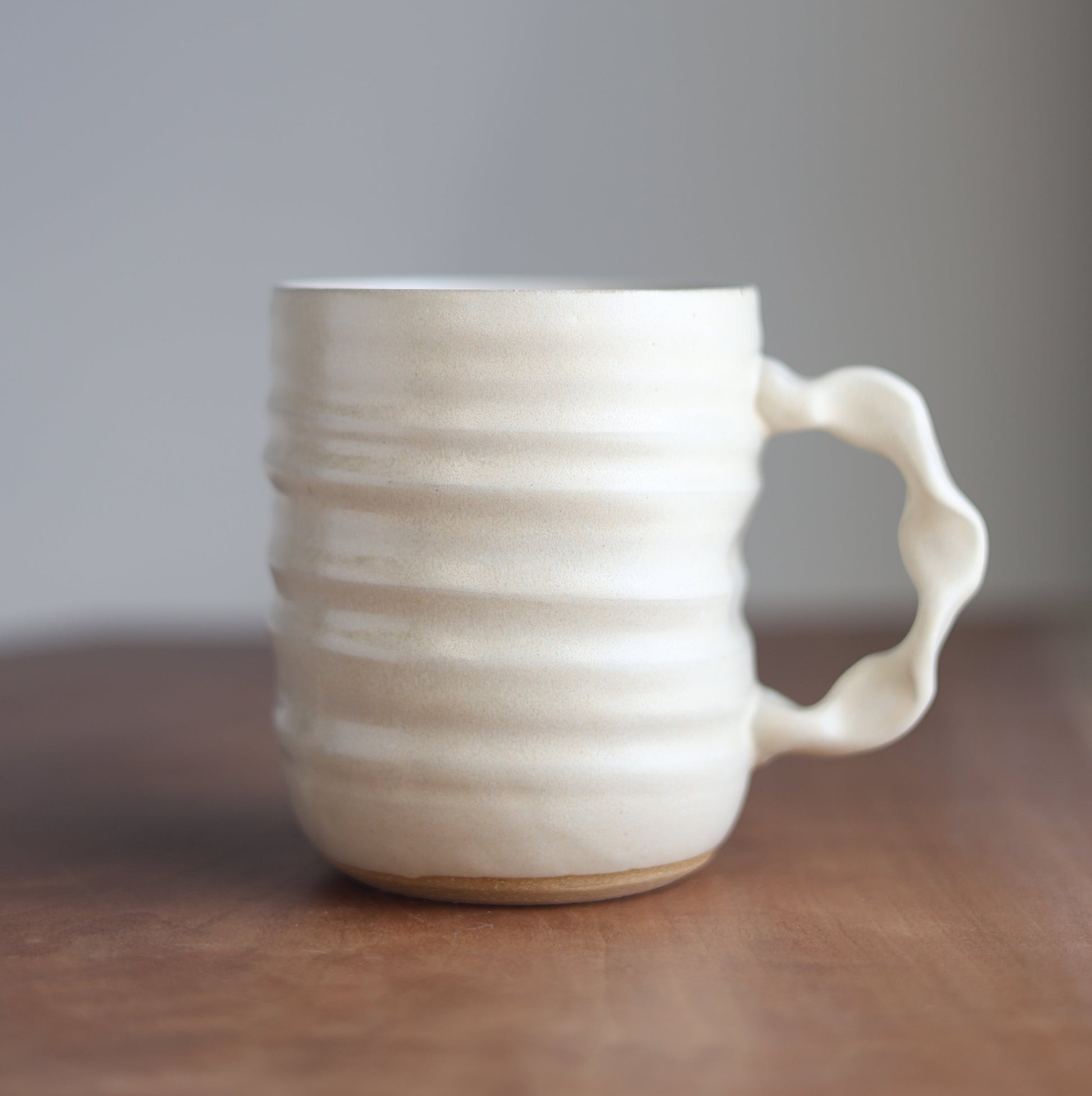 Cream ceramic handmade jumbo companion mug with ribbed design on a wooden surface