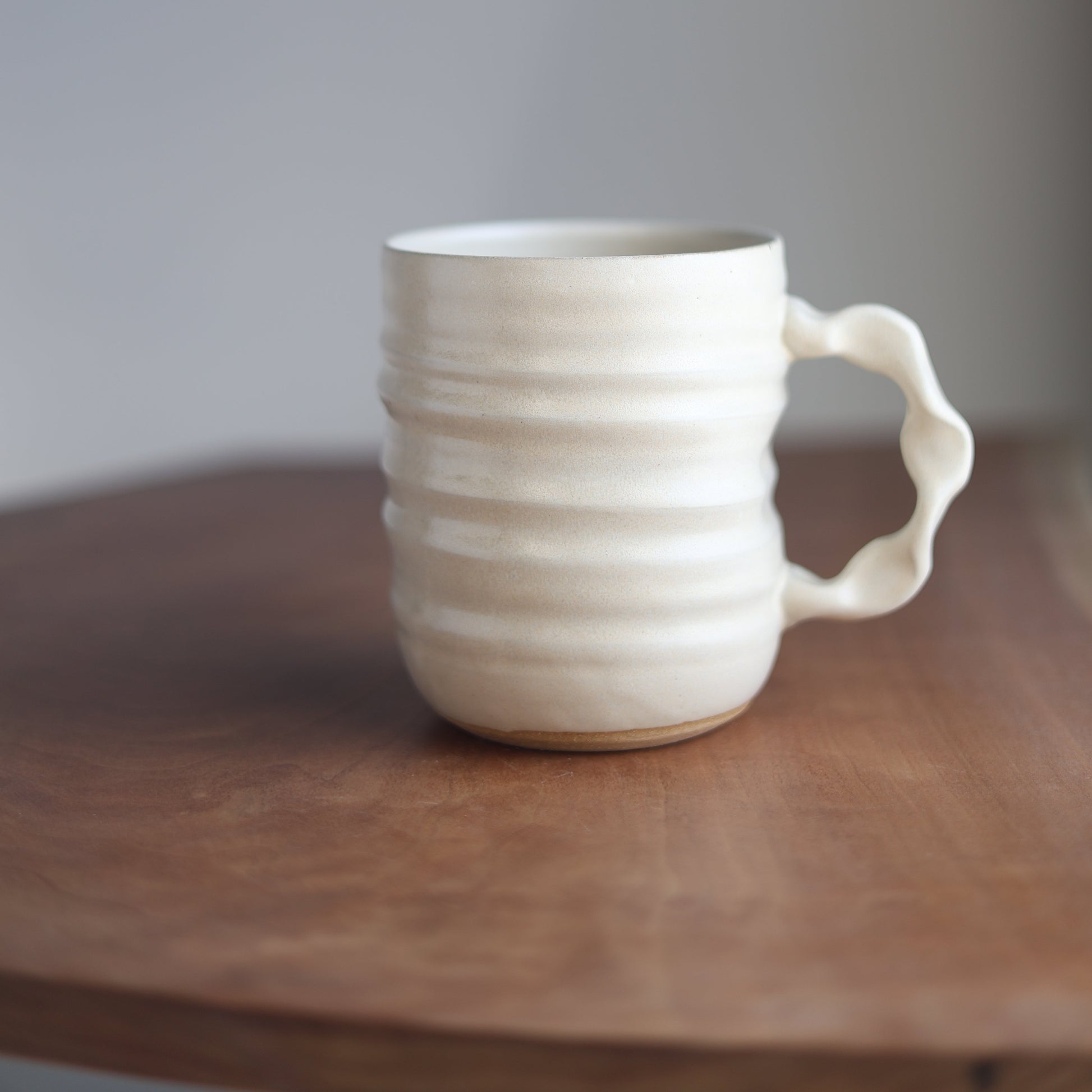 Cream ceramic handmade jumbo companion mug on a wooden surface with a blurred background